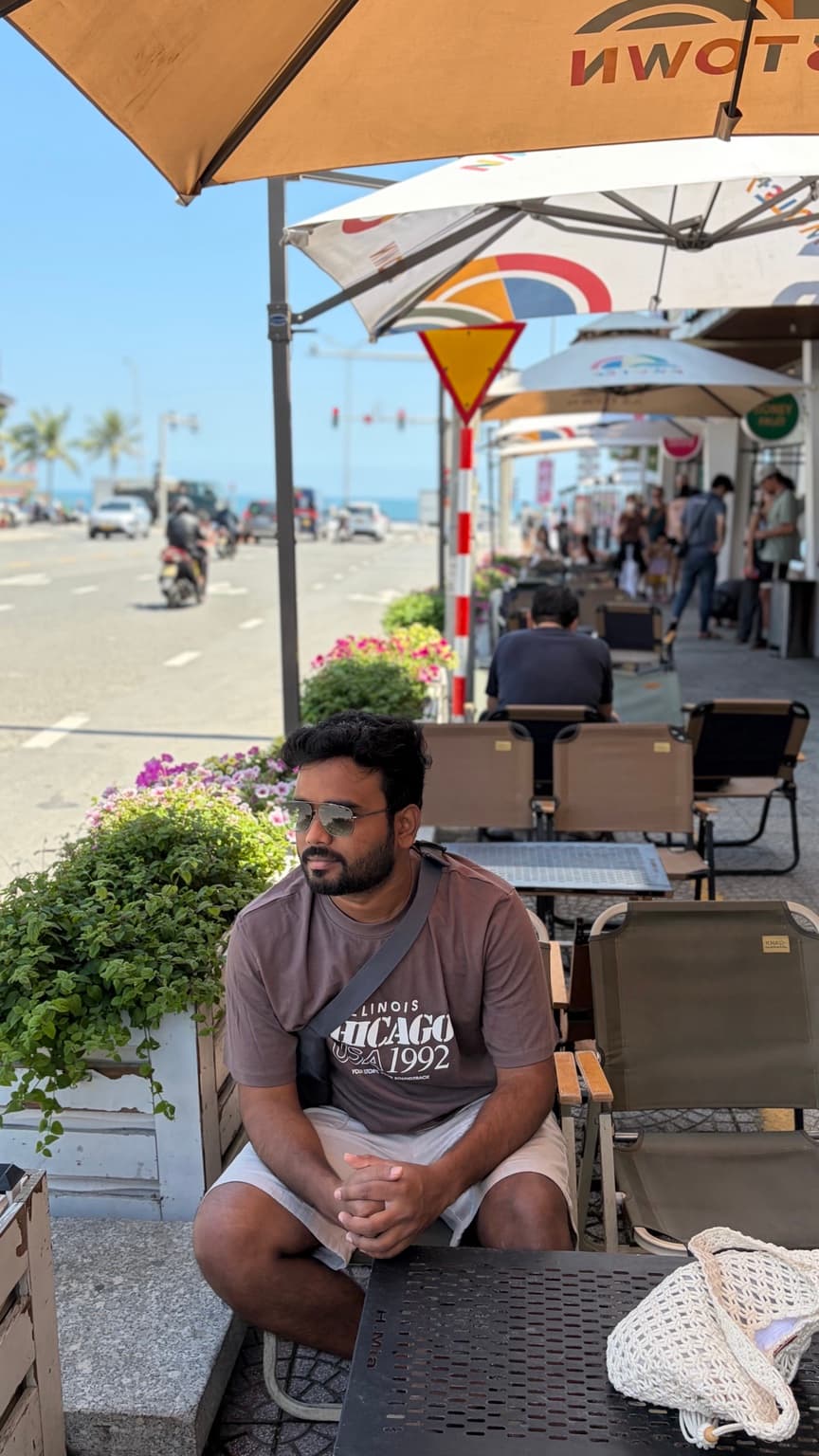 Portrait of Nirmal Kumar G sitting at a seaside café